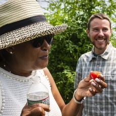 Council member Danah Tench samples a tomato supplied by grad student Jake Bartlett