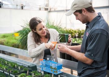 Michelle DaCosta trains student in greenhouse